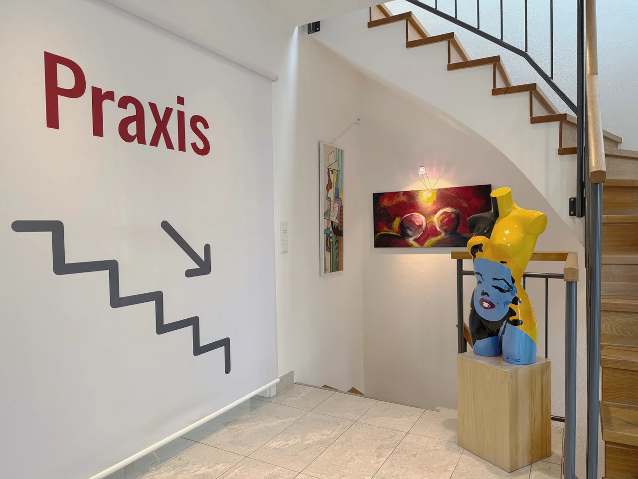 Treppenhaus zur Praxis mit farbiger Skulptur und Kunstwerken