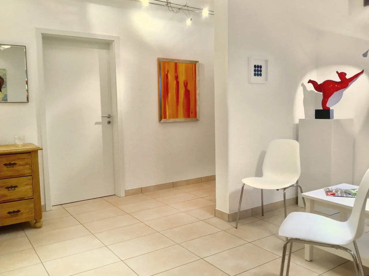 Wartebereich der Praxis mit Kunstwerken und Sitzgelegenheiten